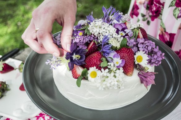 Erdbeer-Torte mit Blumen und frischen Erdbeeren dekorieren